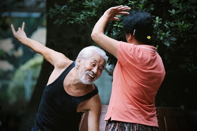 An old Asian man laughing just before he gets hit by a woman in an orange shirt.